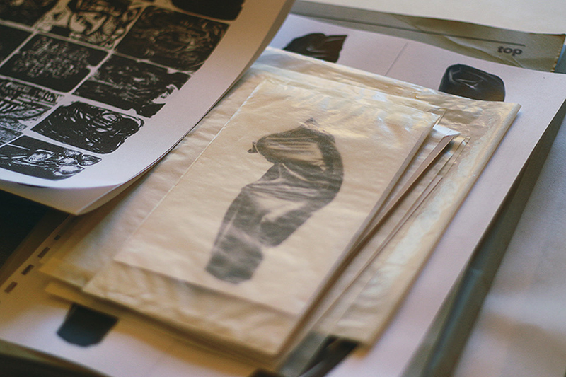 a stack of photographic prints enclosed in a transparent envelope next to lithographic prints