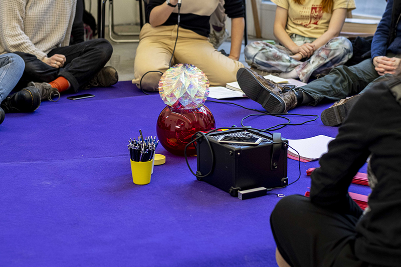 A scultpure that looks like a crystal sits on a purple carped with a speaker next to it. Part of the project 'The Fatigued Compassionate Oracle' by Sickness Affinity group at Berlin Biennale 11