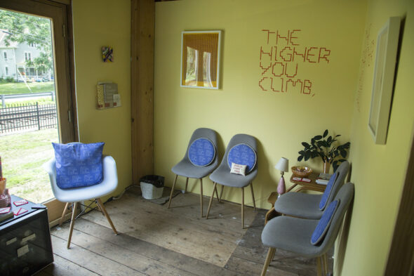 The interior of the lounge featuring chairs, reading materials, lamps, fake plants, candy, and a mini-fridge.