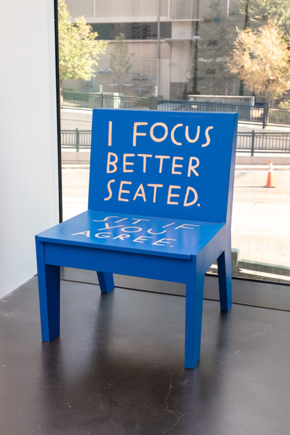 A bright blue chair that says, "I focus better seated. Sit if you agree."