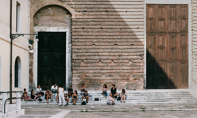 people sit outside an old stone building in venice italy