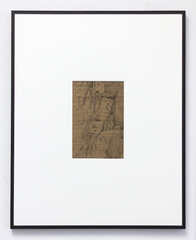 A framed photo of a black line drawing on brown wood of a bunker.