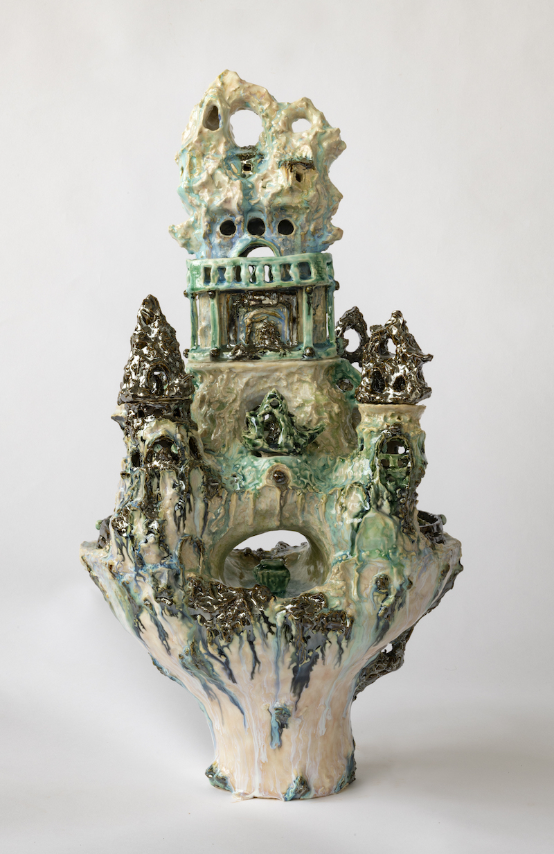 a detailed image of a ceramic vessel that looks like a small palace, in shades of beige and turquoise