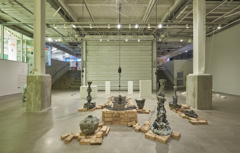 a view of several ceramic sculptures displayed in an exhibition room with two large columns framing them