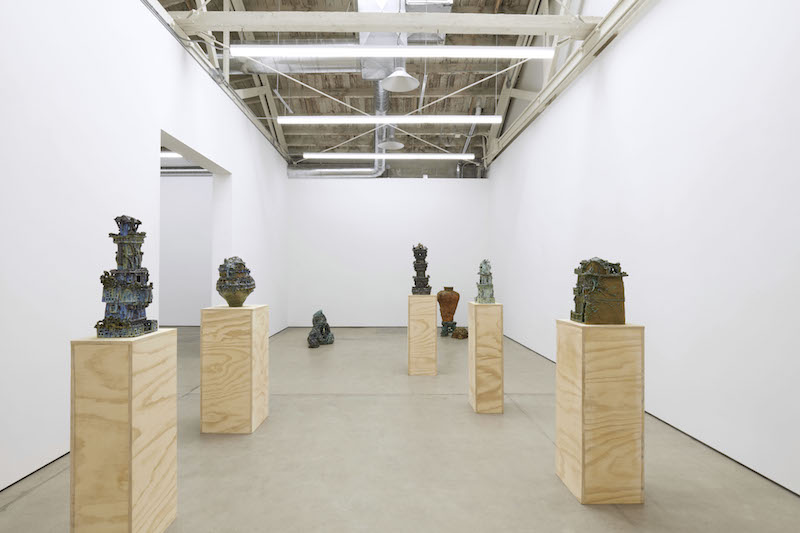 a white walled gallery space with several pedestals holding ceramic sculptures