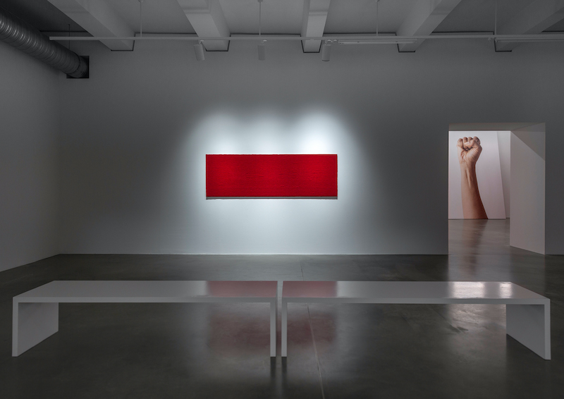 An installation view at KINDL of a red textile and fist in the background.