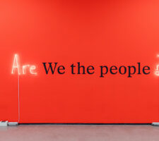 "Are we the people?" is written on a red wall.
