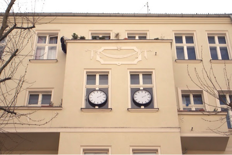 a building facade with two large black and white clocks installed on its windows