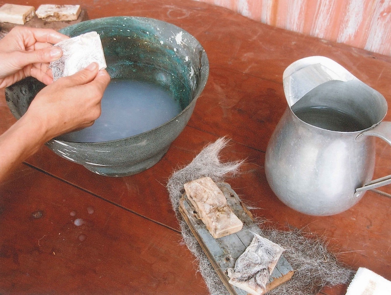 two hands over a wash basin, scrubbing with ass milk soap