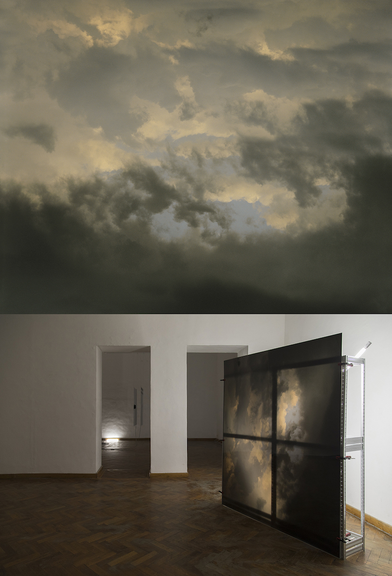 a photograph of a dark cloudy sky mounted on plexiglass in a gallery room