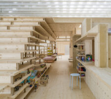 a view of the wooden construction inside with a stool and kids toys on the shelves