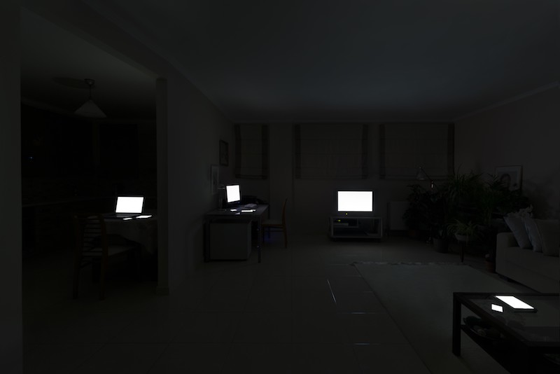 several white screens are lit up in  different parts of a dark room