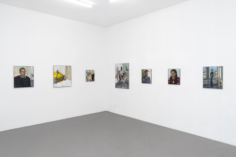a photo of several small painted portraits on a white gallery wall
