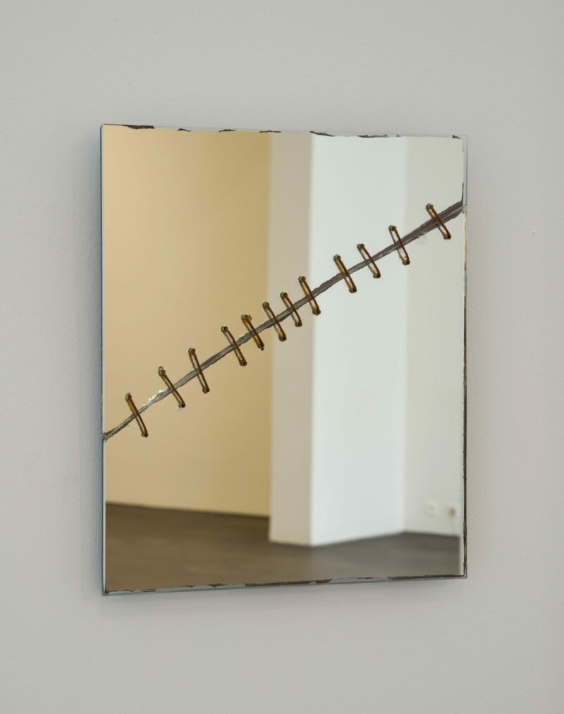 Broken and stapled mirror on a white wall