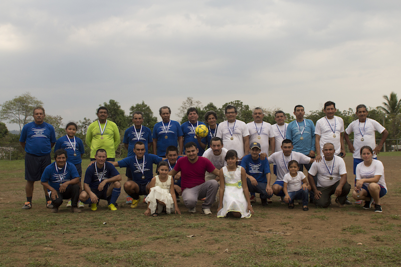a group of people pose for a photo on a soccer field
