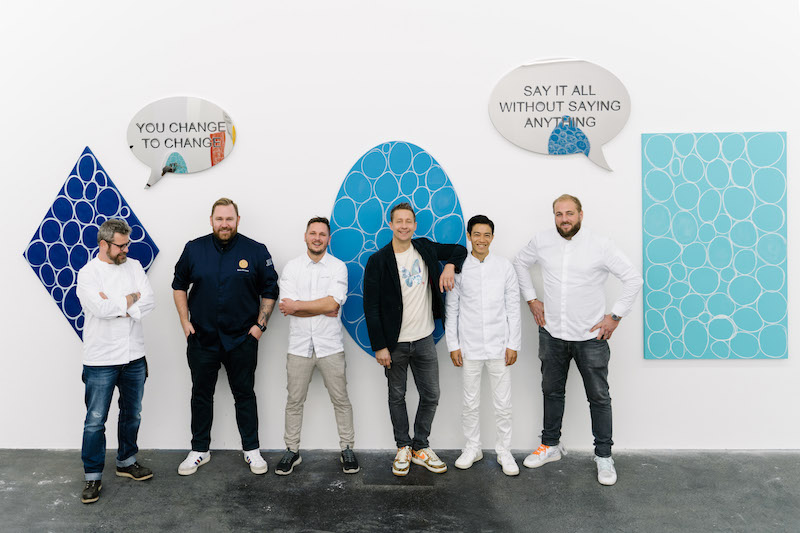 five chefs stand with jeppe hein in front of the artwork in his studio in berlin
