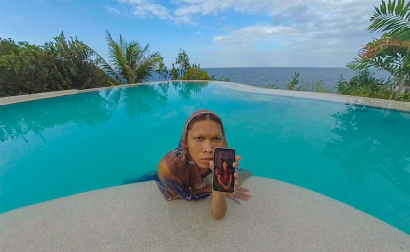 Woman in a pool holding a smartphone toward the camera