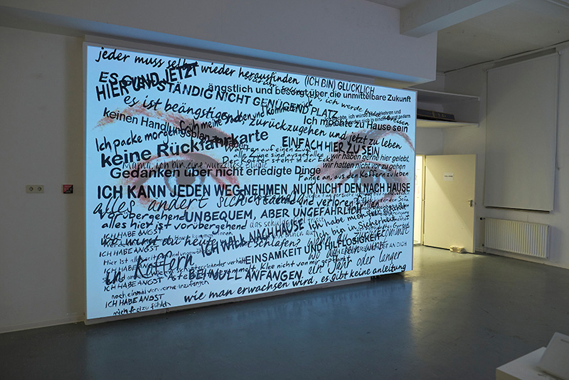 A wall with a projection of two eyes and text layered overtop.