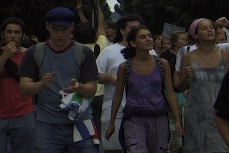 a video still depicting many people walking in protest