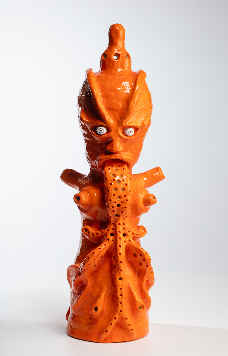 an orange ceramic sculpture of a pseudo demonic vomiting figure