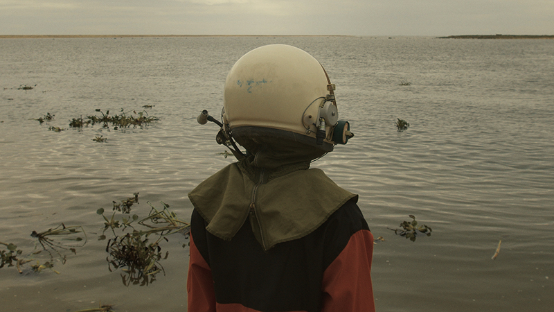 a deep sea diver with their helmet on shown from  behind looking out at the sea