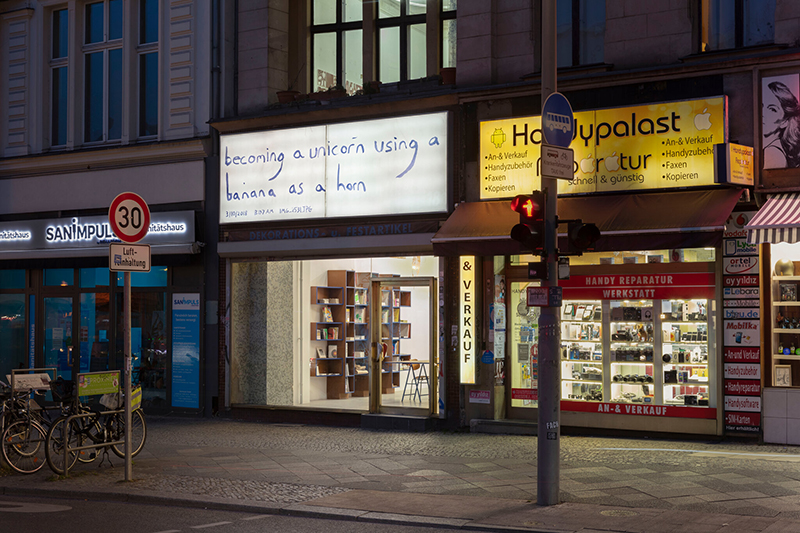 street level shop front with an illuminated sign board above