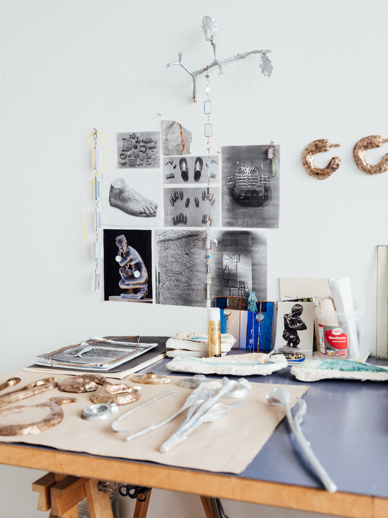 Photo of a desk with small bronze sculptures on it and photos hanging in the background