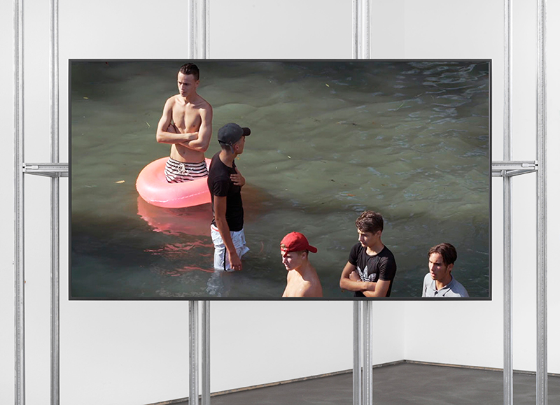 a flatscreen monitor showing teenage boys in dirty water