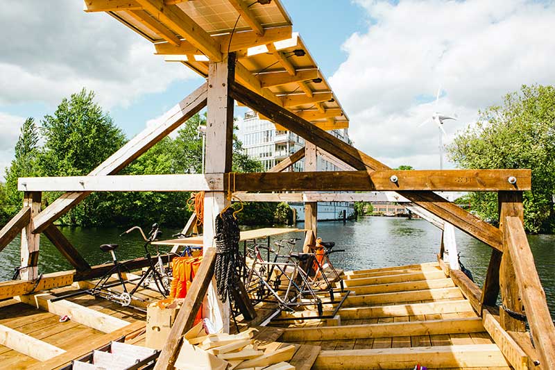 The interior of a make shift, raft-like wooden boat with a table and bicycles on it