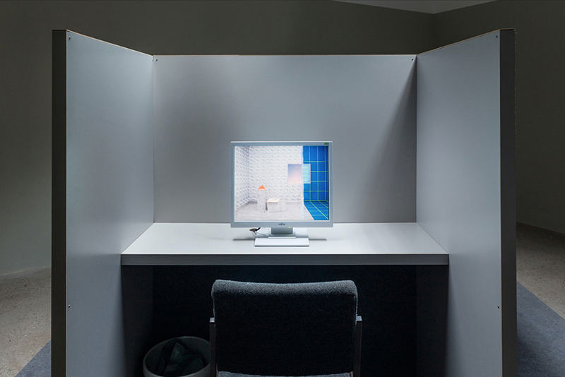 a cubical with a computer screen showing the virtual room that actually is a real room built to look fake