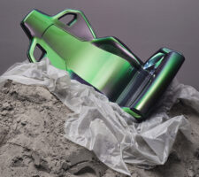 a green shiny gaming chair on a piece of plastic on sand