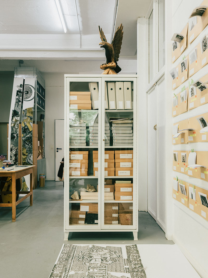 A photograph of a closed archive closet with glass doors and a wooden eagle on top