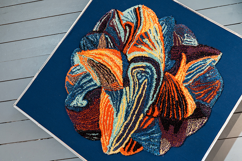 An irregularly shaped handmade rung on a blue platform photographed from above