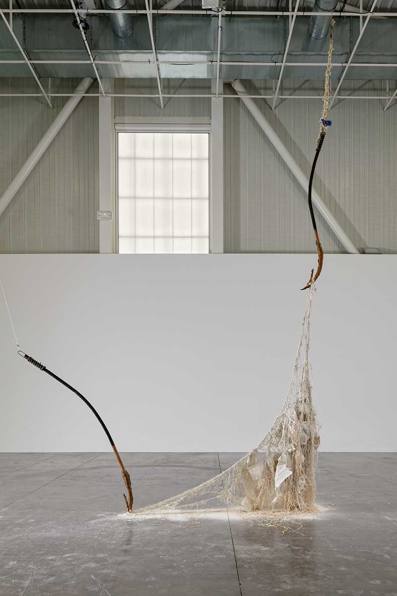A sculpture in a large gallery space made of wood and nets
