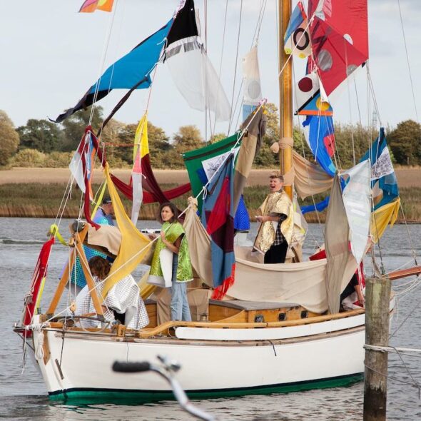 People on an art installation of a boat with colorful fabrics in Arnis, Germany