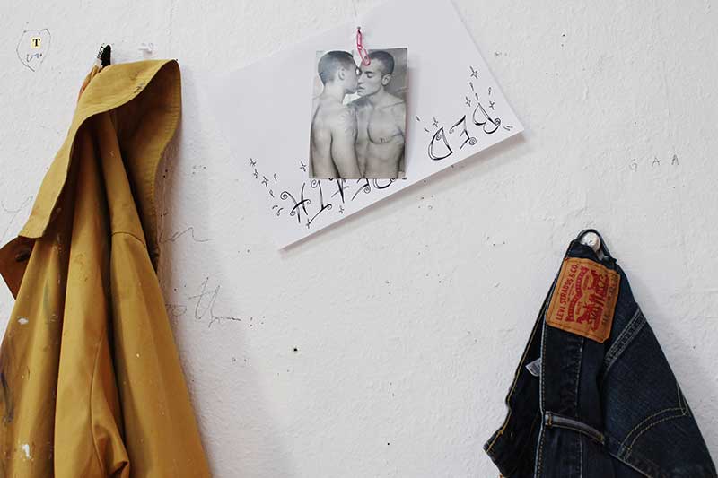 Close up of a photo of two men kissing pinned to a wall