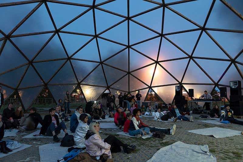 People sitting on the ground under a translucent dome