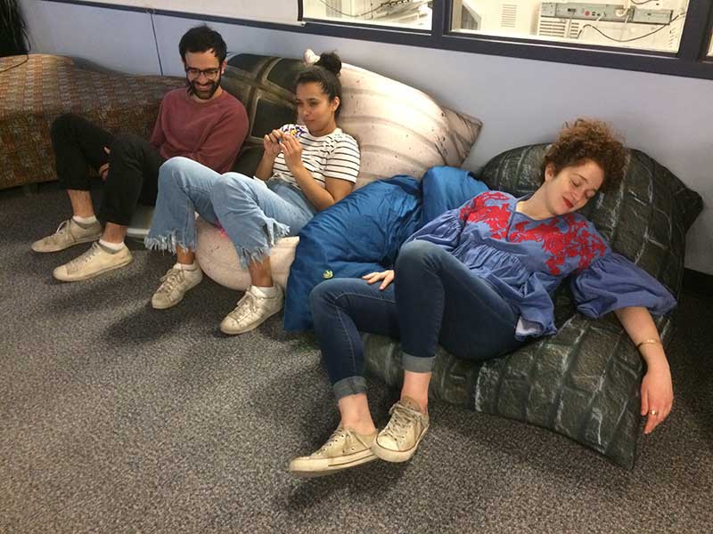 Three young people relaxing on large bean bag pillows on the floor