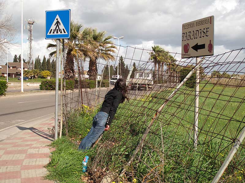 A photograph of a woman leaning into a wire fence