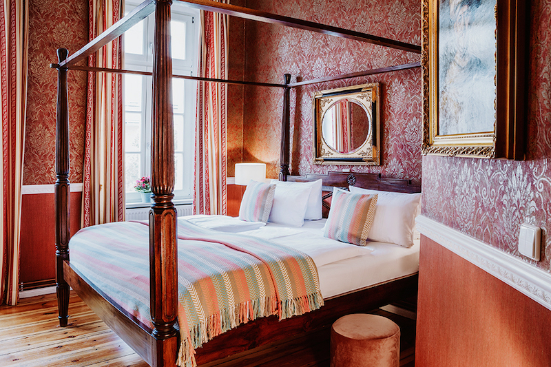 19th Century style hotel room with a double bed with a wooden frame