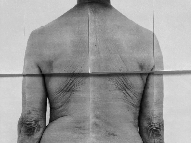 Part 6 of Photo Essay by Sophie Jodoin. It is a black and white image of four papers placed together upon which a photograph of an older woman's back is depicted