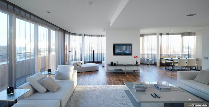 modern design hotel suite with large windows television at the wall, white lounge sofas