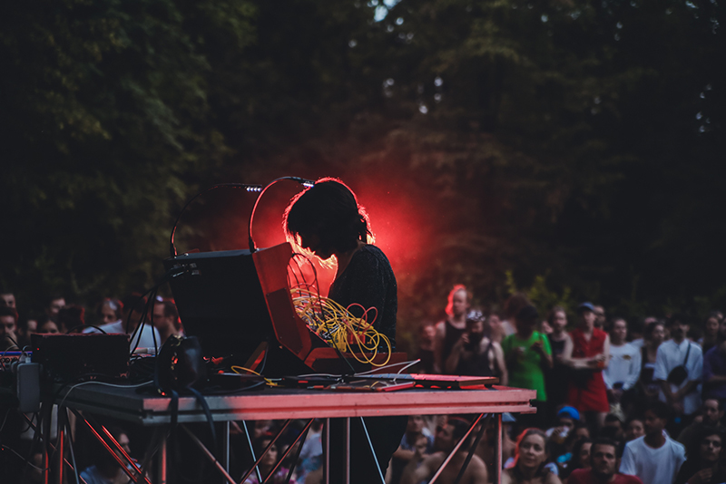 The silhouette of a woman playing a buchla instrument outside at a festival on stage