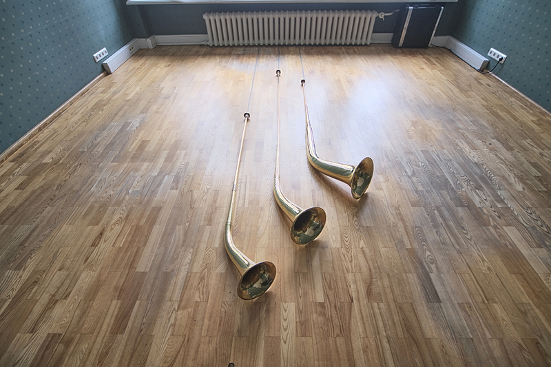 three augmented brass horns lying on a hardwood floor