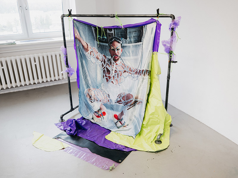 A material with a photo of a man dressed for a rave is hung on a metal frame