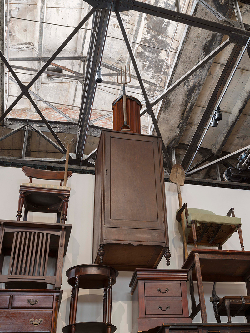 A close up of furniture piled atop each other into a pyramid-like construction with a pitchfork at the very top