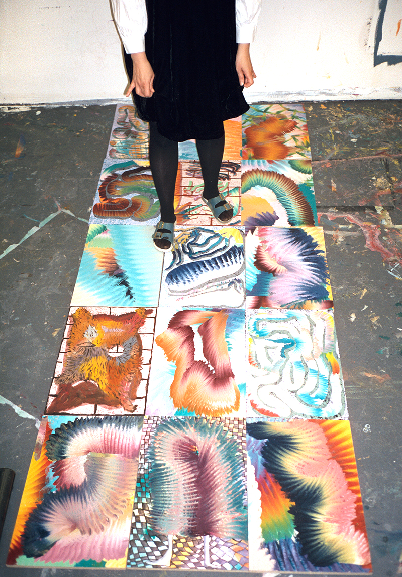 A photo of a woman's legs standing on paintings on the floor