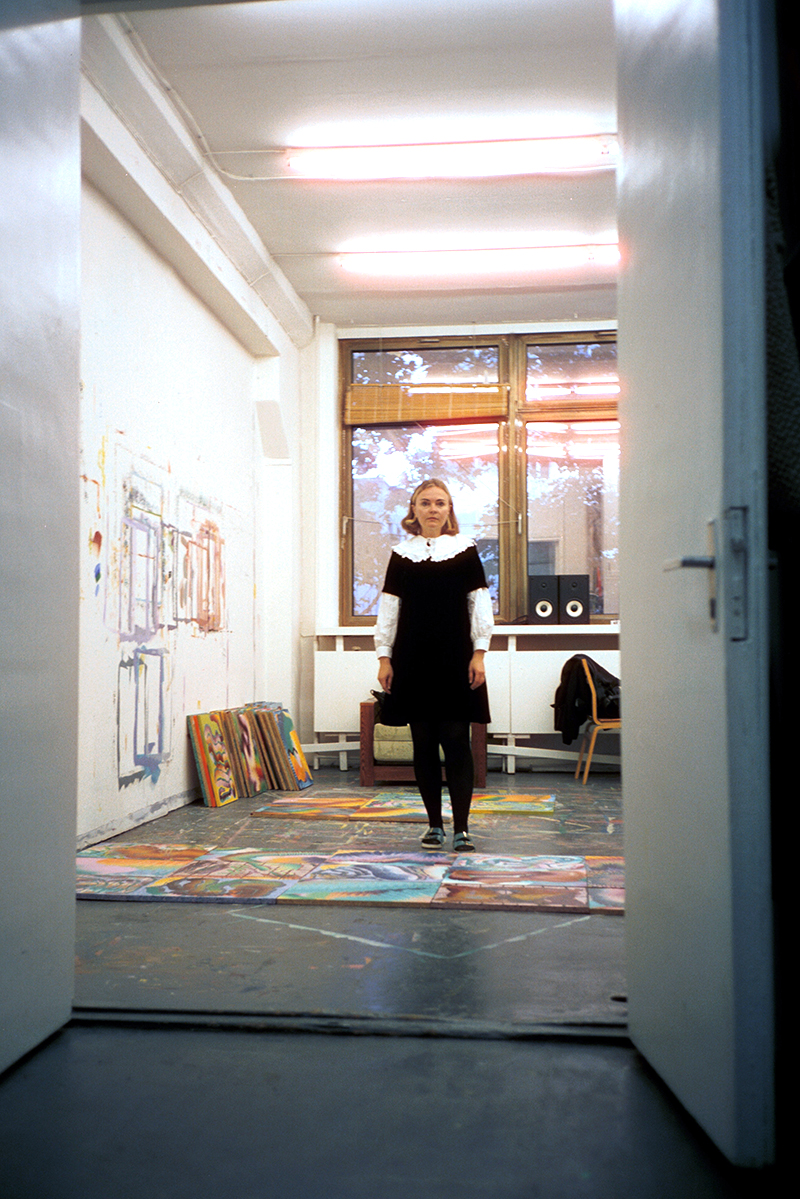 A woman standing in a painter's studio.