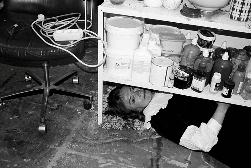 a black and white photo of a woman under a shelf