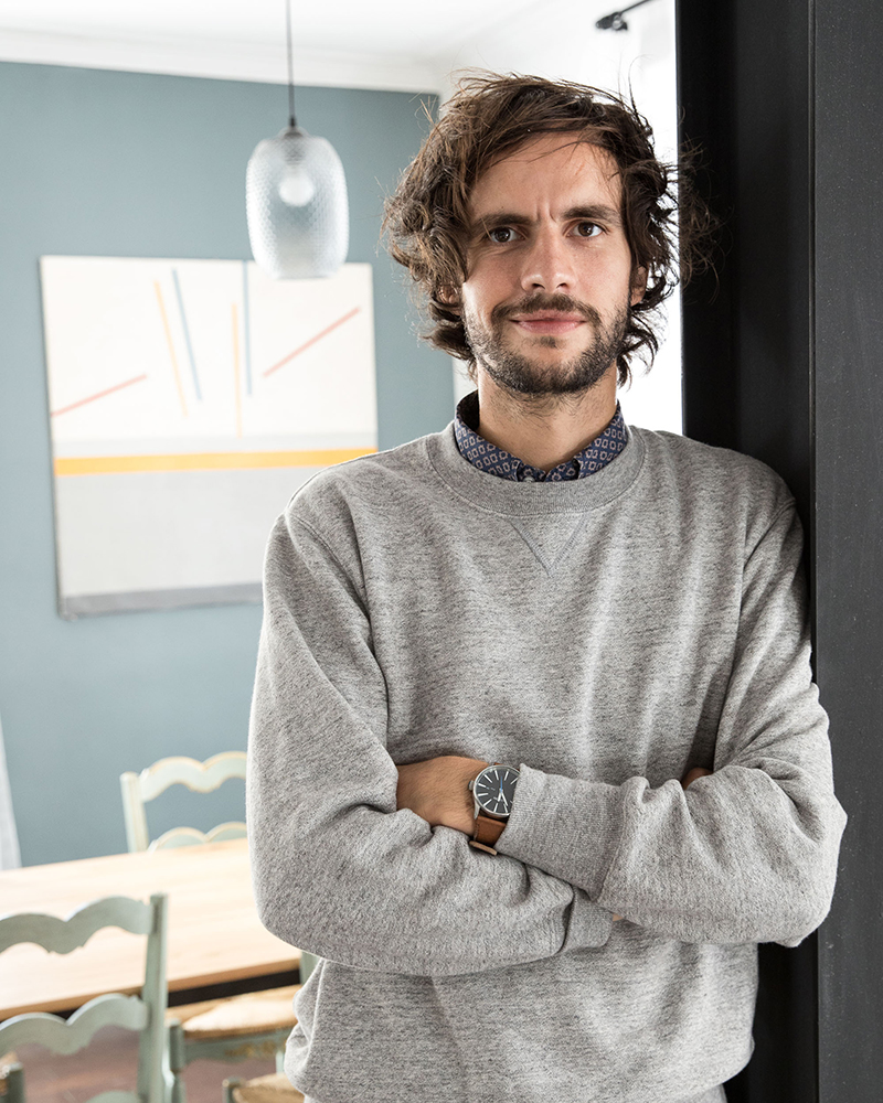 Portrait of a young man with a beard and disheveled hair standing in a doorway